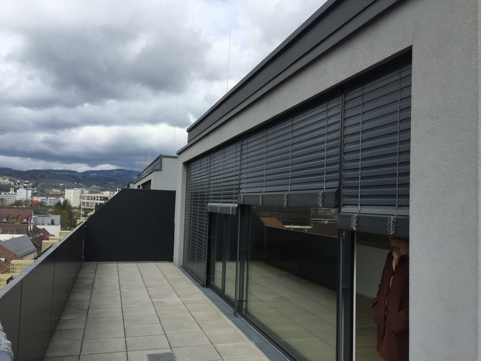 Anthrazitfarbene Raffstoren an einem modernen Penthouse mit Blick über Linz